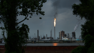 A flame of fire above a waterside factory.