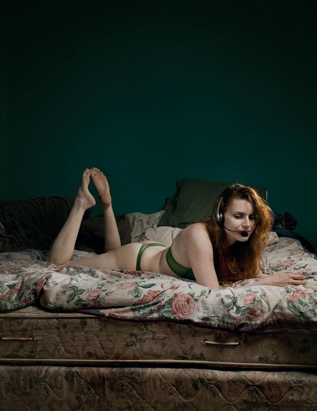 Woman in underwear laying in bed, wearing hands-free phone headset.