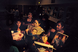 Kettleman City mothers—including Magdalena Romero, left, and Maura Alatorre, center—show photos of their babies to epa officials.
